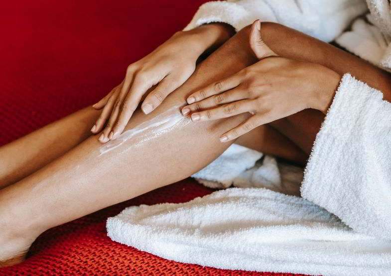 Mujer extendiendo crema de cáñamo en sus piernas