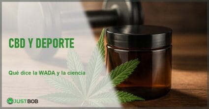 Hoja de cannabis sativa y un frasco de vidrio ámbar junto a una mancuerna de gimnasio sobre una mesa de madera, en alusión al CBD y el contexto deportivo